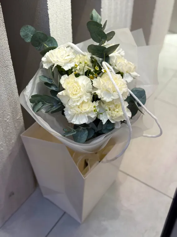 Белые розы с тёмной зеленью в светлой упаковке