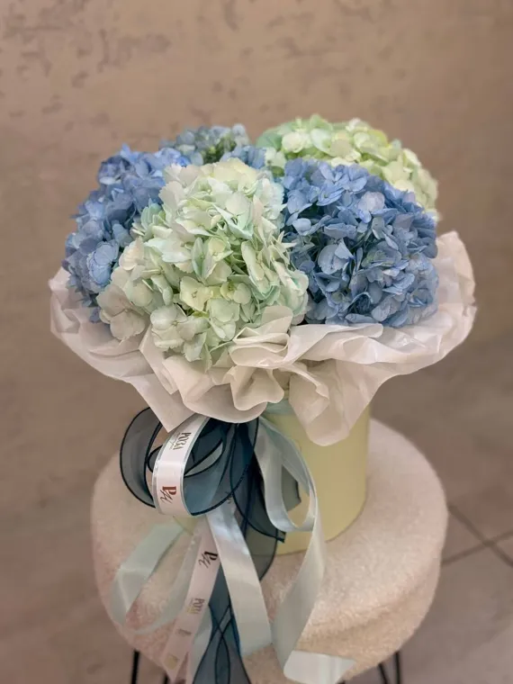 Голубые и белые соцветия в светлом букете с лентами