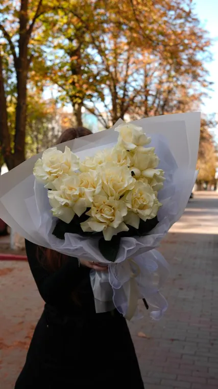 Кремовые розы в светлой упаковке на фоне осенних деревьев